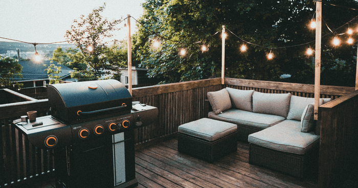 Terraza con guirnaldas de luces, sofá esquinero exterior, barbacoa eléctrica